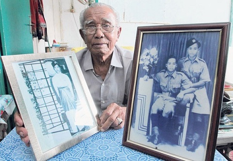 Tok Ujang showing old portraits of his family