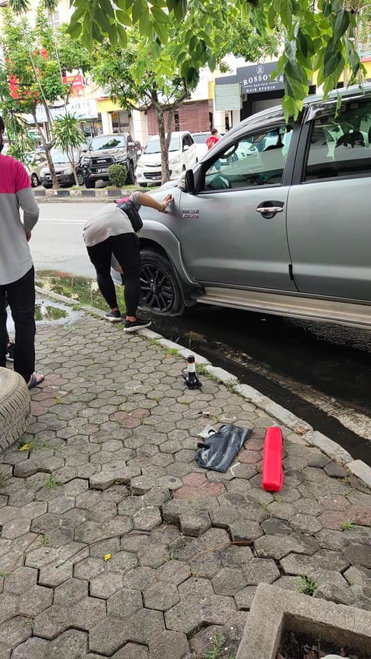 Foodpanda riders fixing punctured vehicle tyre on the road