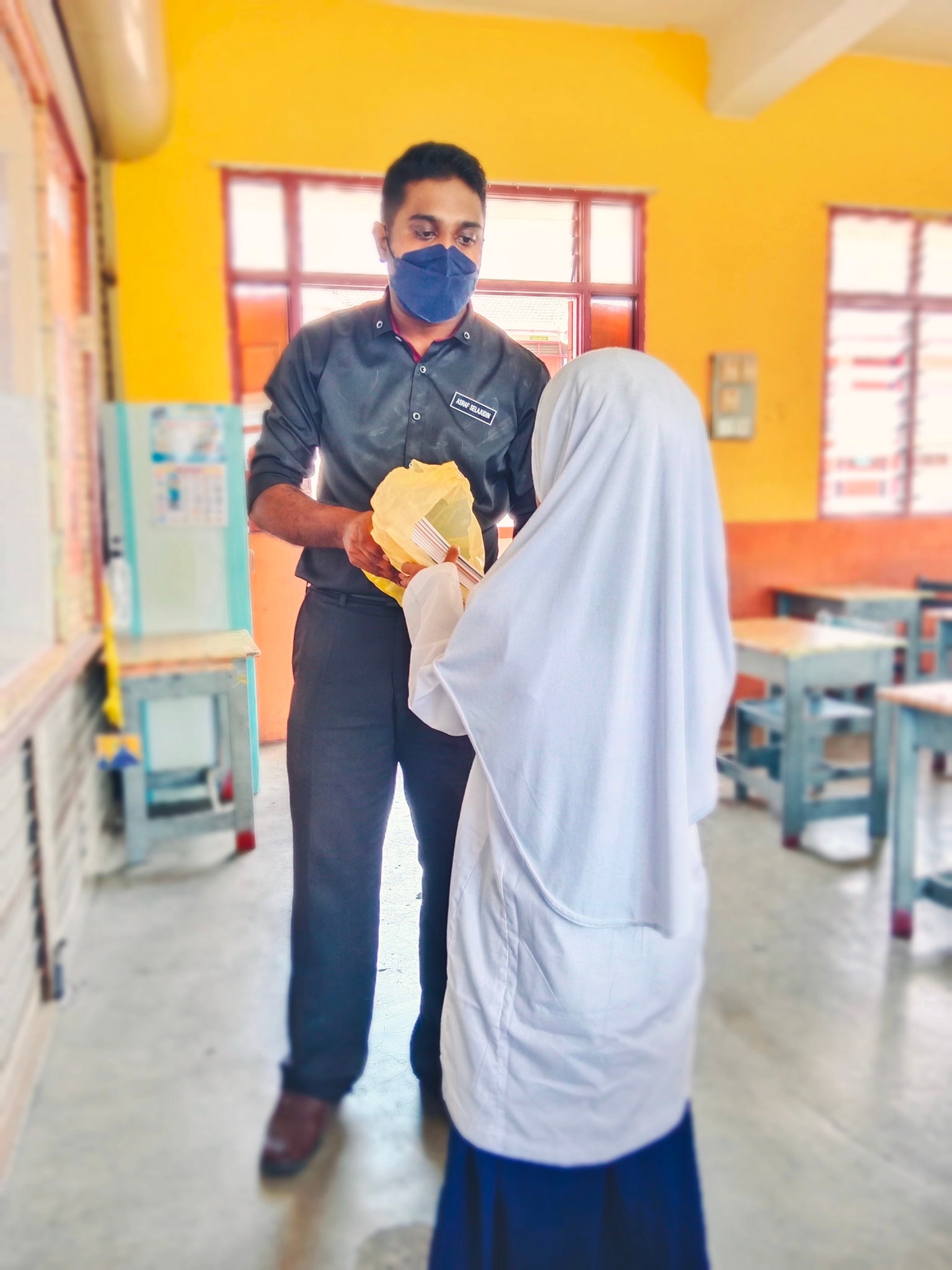 Cikgu Asraf buys notebook for his student