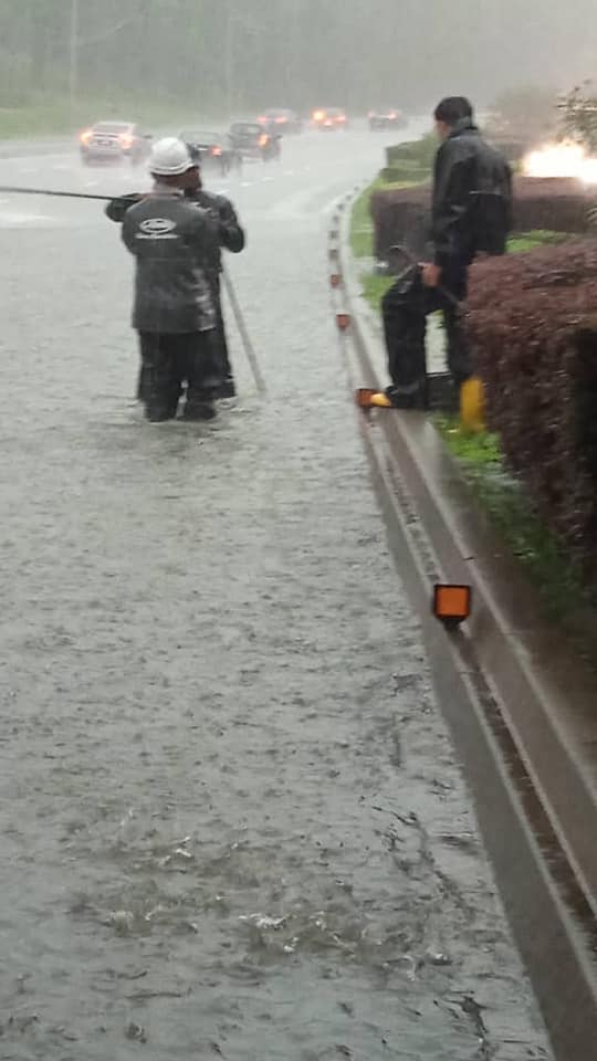 Sanitation workers on flooded road