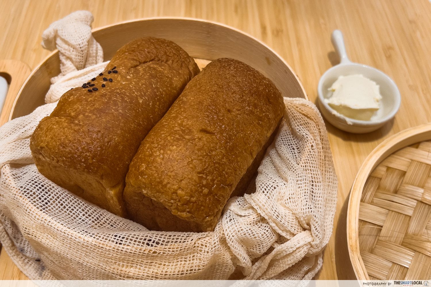 steamed bread in a bamboo basket with a cream on the side