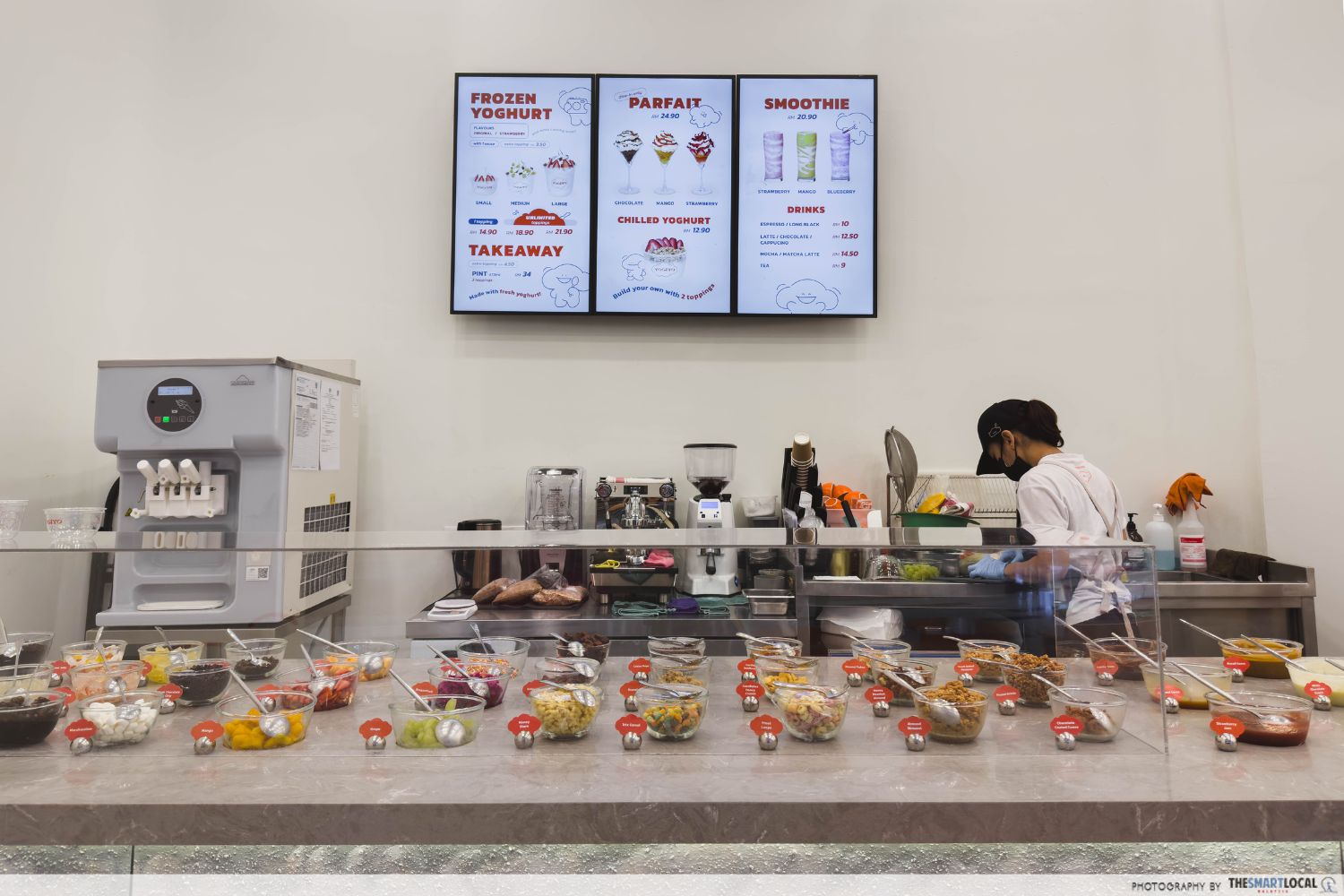the counter view of yogiyo, with bowls of toppings arranged neatly on the countertop, and the menu on the wall, the staff is prepping the ingredients