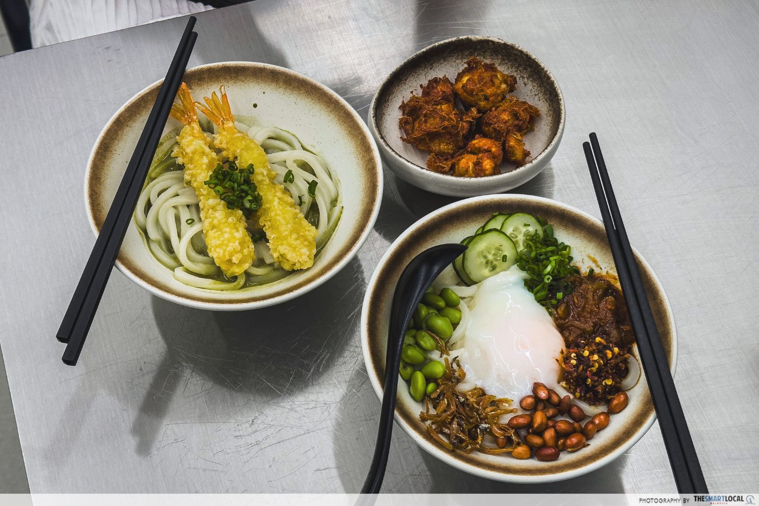 a bowl of udon swamped in matcha soup, topped with tempura; a bowl of udon topped with onsen egg and nasi lemak ingredients; a bowl of fried chicken
