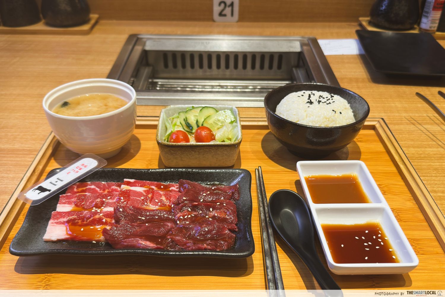 yakiniku set meals with rice, miso soup, salad, condiments, and a plate of beef short plates and skirts