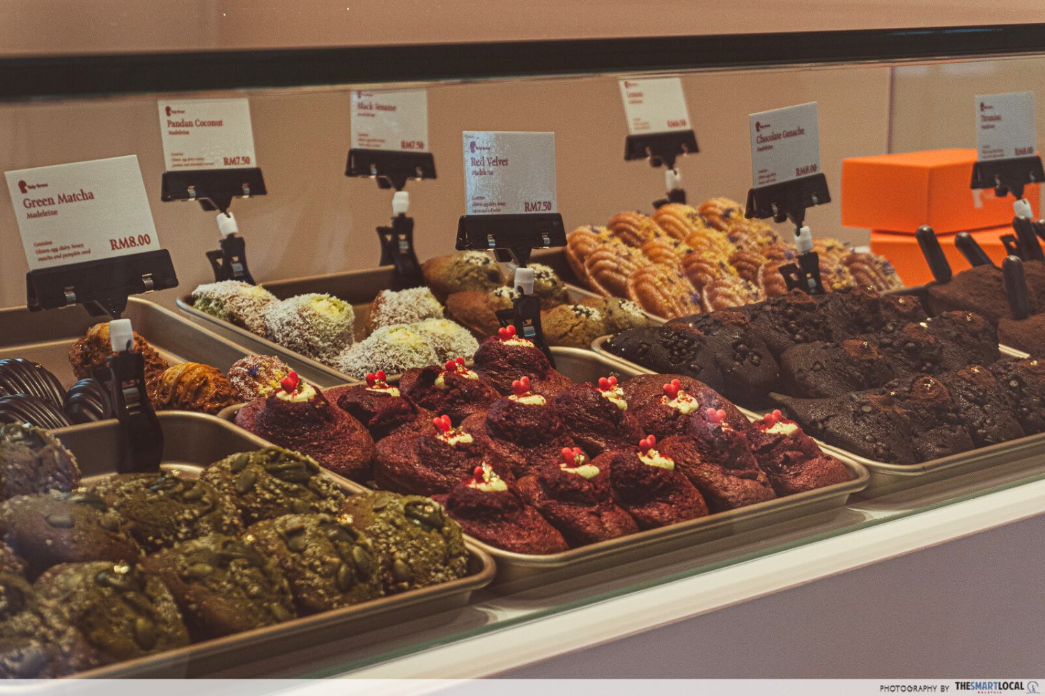 display of bake brown madeleine flavours on the counter with see-through glass case