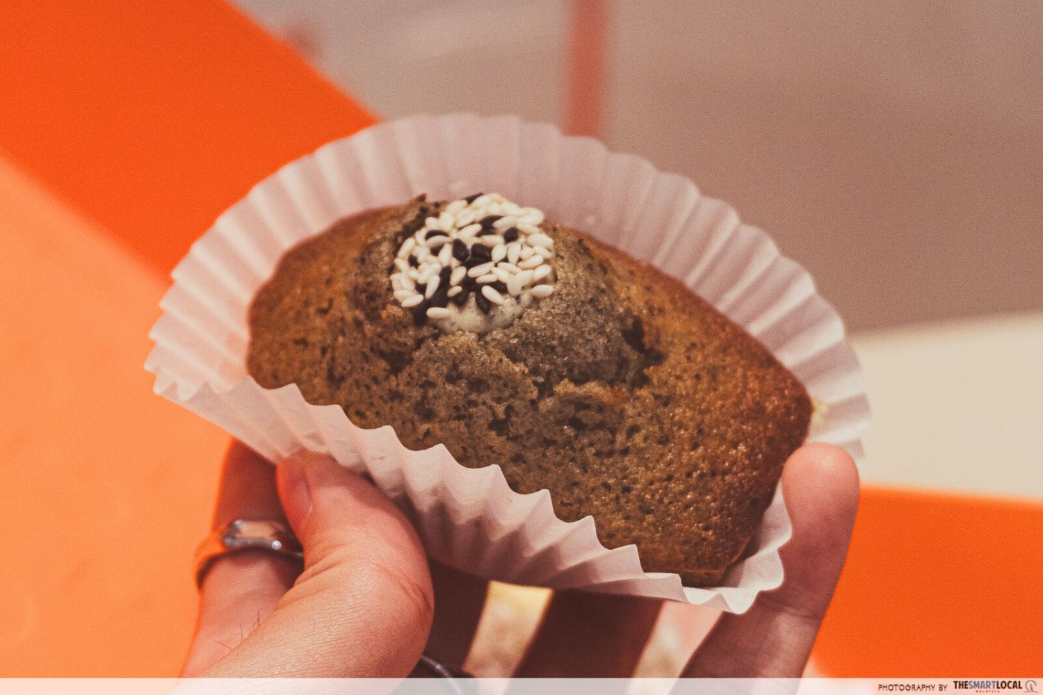 a black sesame madeleine sprinkled with sesame seeds and filled with black sesame cream