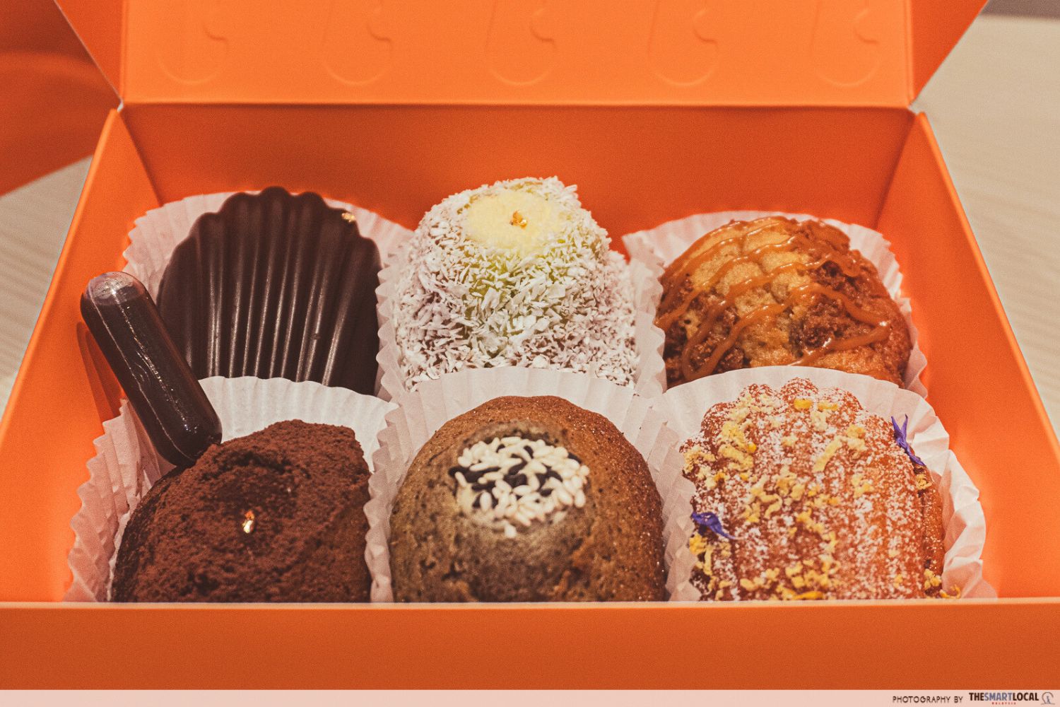 a box of six madeleine with assorted flavours including seashell chocolate and pandan coconut